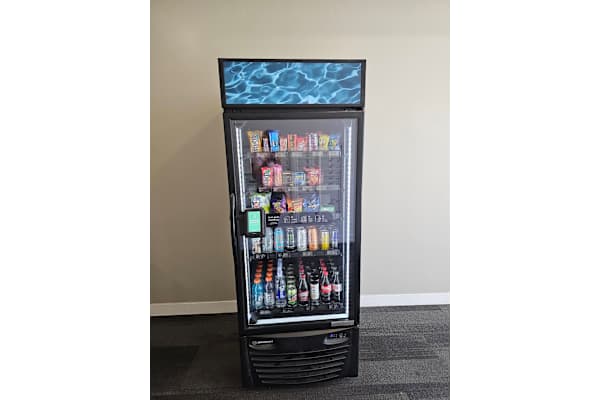A black and silver vending machine with a glass door filled with drinks. at 605 Place Student Housing & Co-Living, St George